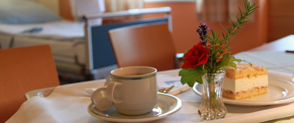 Tisch gedeckt mit Kaffee und Kuchen sowie Blumenschmuck